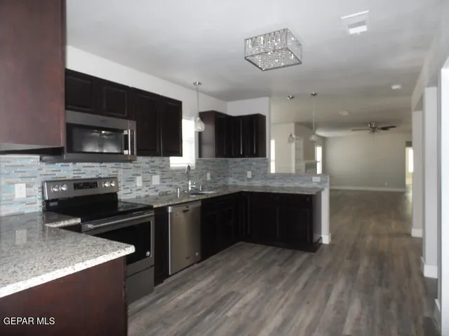 a kitchen with stainless steel appliances kitchen island granite countertop a stove and cabinets
