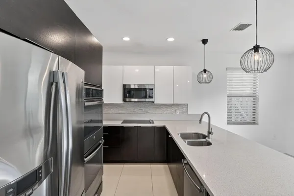 a kitchen with stainless steel appliances granite countertop a sink a refrigerator and a stove top oven