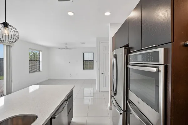 a large kitchen with kitchen island a large counter space a sink appliances and a chandelier