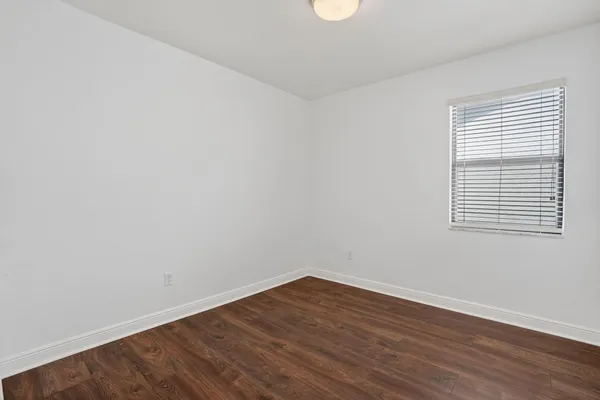 an empty room with wooden floor and window