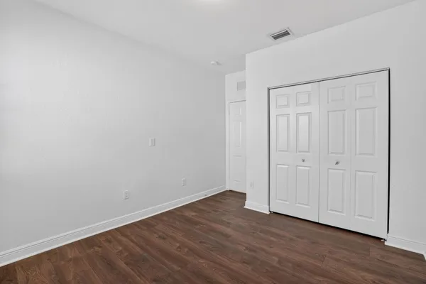 a bedroom with a bed wooden floor and a window