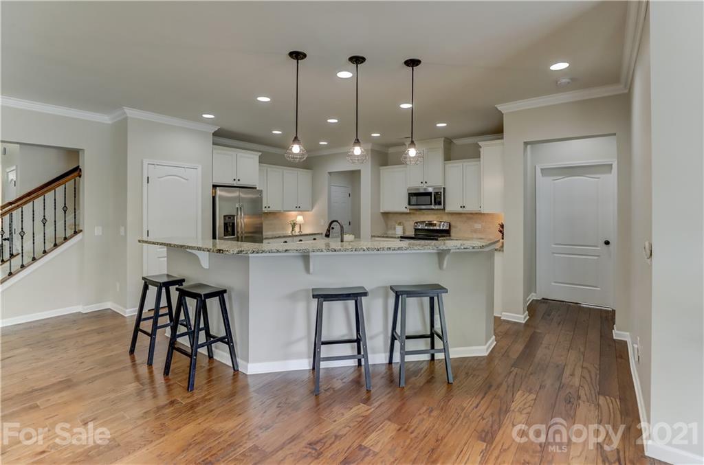 5202 Waterloo Drive Tega Cay, SC 29708 - Photo 16 of 44 a kitchen with stainless steel appliances granite countertop a stove a sink a refrigerator and a dining table with wooden floor