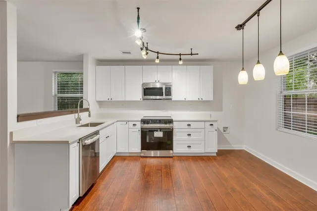 a kitchen with stainless steel appliances granite countertop a stove a sink and a wooden floor