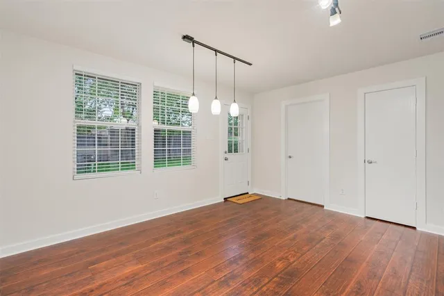a view of an empty room with wooden floor and a window