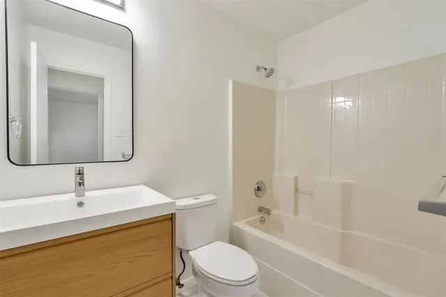 a bathroom with a toilet sink vanity tub and mirror