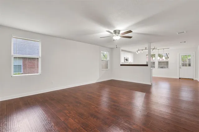 a view of an empty room with a kitchen and wooden floor