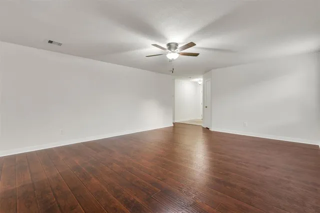 an empty room with wooden floor and a ceiling fan