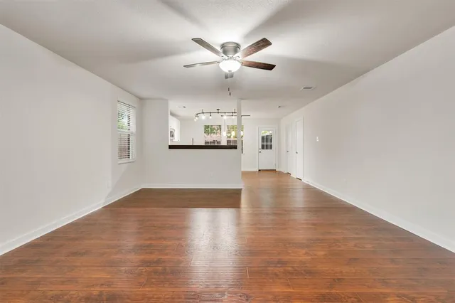 a view of empty room with wooden floor and ceiling fan