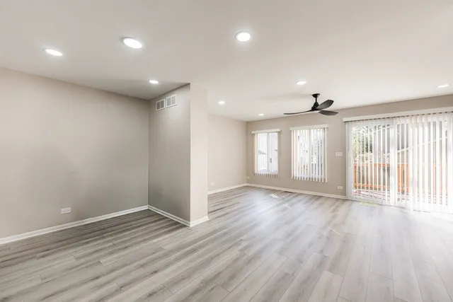 a view of an empty room with a window and wooden floor
