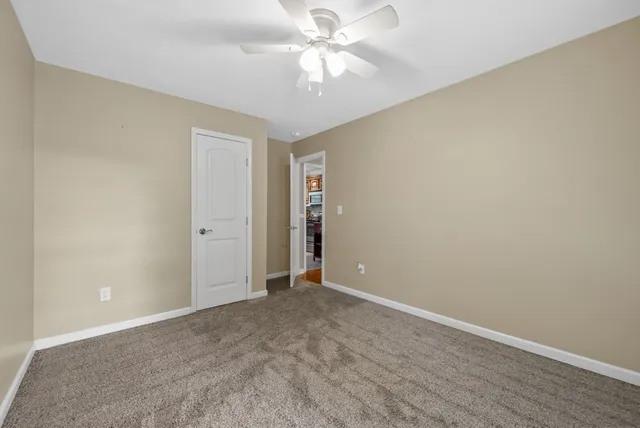 a view of an empty room and chandelier fan