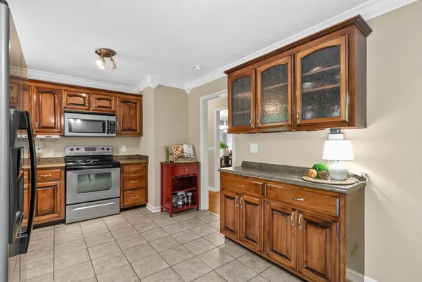 a kitchen with stainless steel appliances granite countertop a stove top oven a sink dishwasher a dining table and chairs with wooden floor