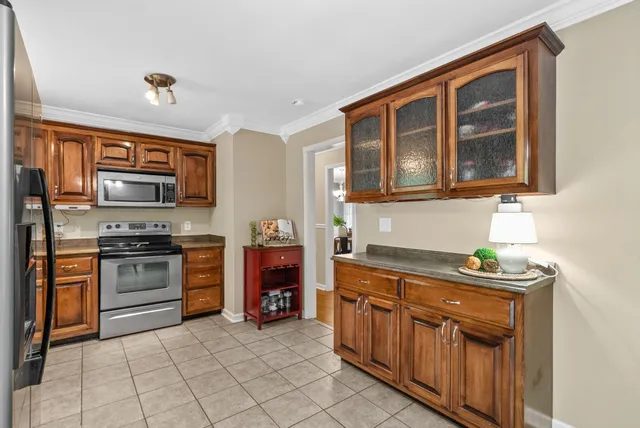 a kitchen with stainless steel appliances granite countertop a stove top oven a sink dishwasher a dining table and chairs with wooden floor