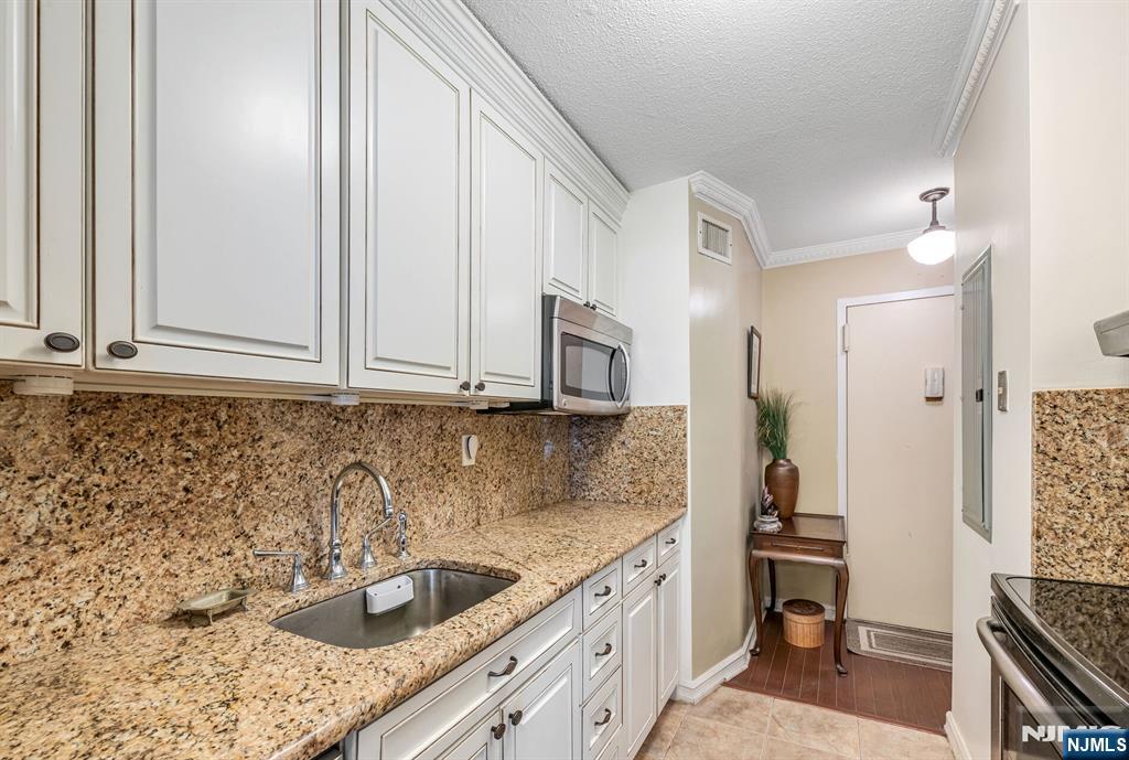 125 Prospect Avenue, Unit 16C Hackensack, NJ 07601 - Photo 21 of 35 a kitchen with stainless steel appliances granite countertop a sink stove and cabinets
