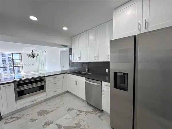 a kitchen with granite countertop a refrigerator and cabinets