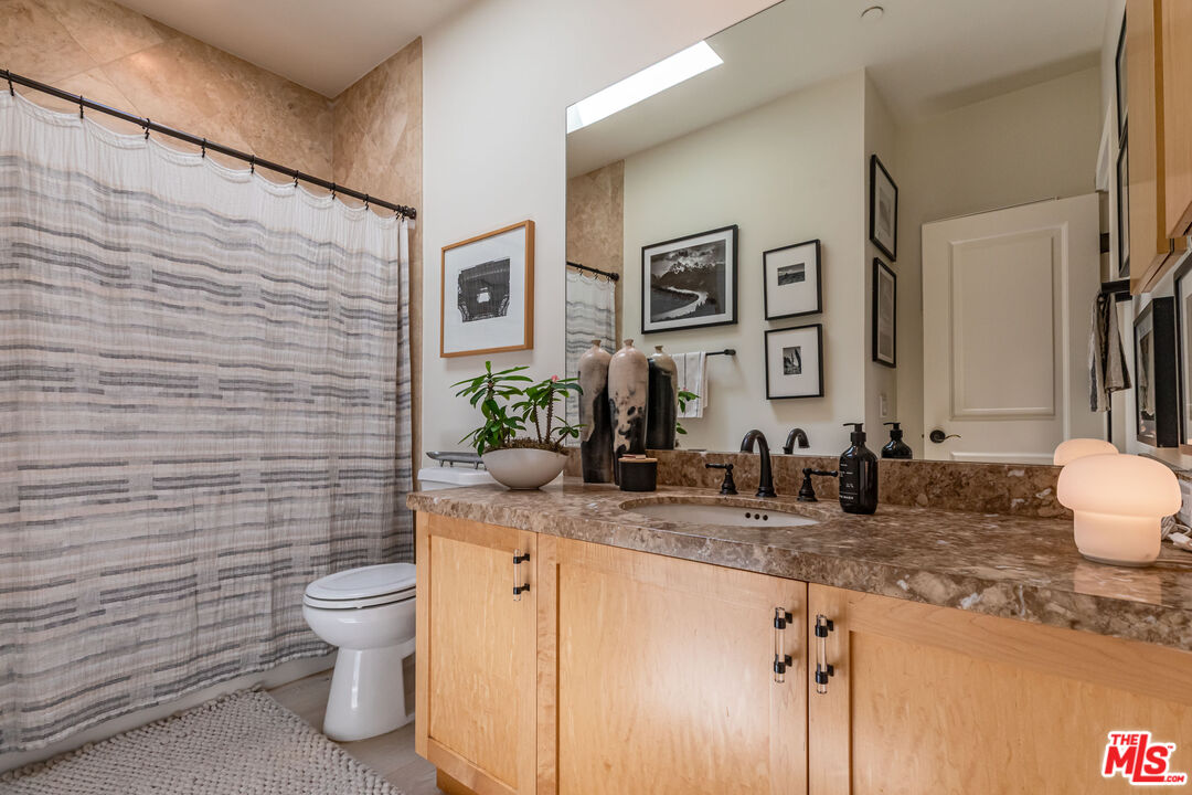 1045 Cold Canyon Road Calabasas, CA 91302 - Photo 33 of 51 a bathroom with a granite countertop toilet sink and mirror