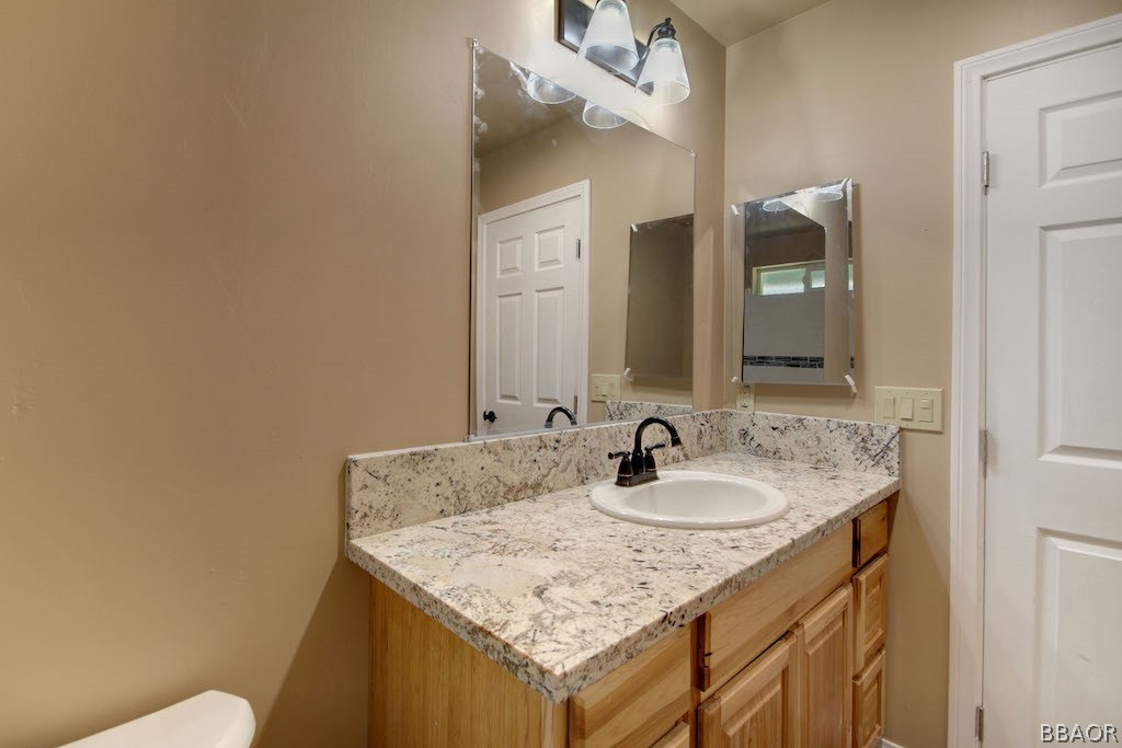 369 Riverside Avenue Sugarloaf, CA 92386 - Photo 26 of 30 a bathroom with a granite countertop sink and a mirror