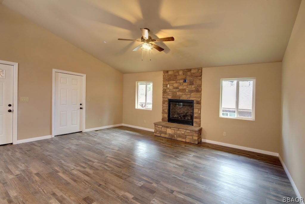 369 Riverside Avenue Sugarloaf, CA 92386 - Photo 5 of 30 an empty room with windows fireplace and wooden floor