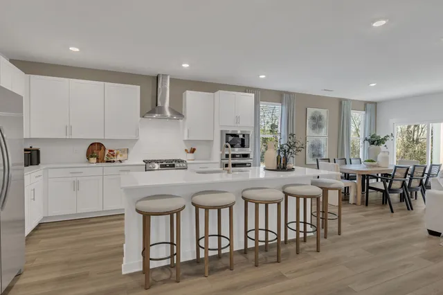 a kitchen with stainless steel appliances granite countertop a dining table chairs stove refrigerator and cabinets