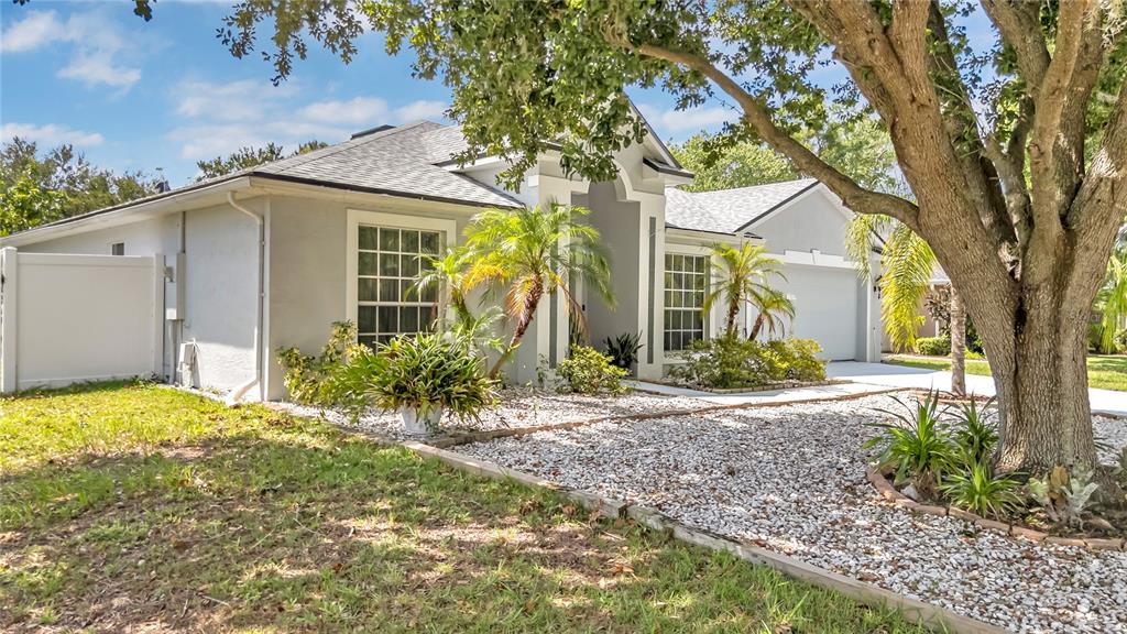 a view of yellow house with a yard and large tree