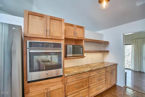 a kitchen with granite countertop cabinets stainless steel appliances and a wooden floor