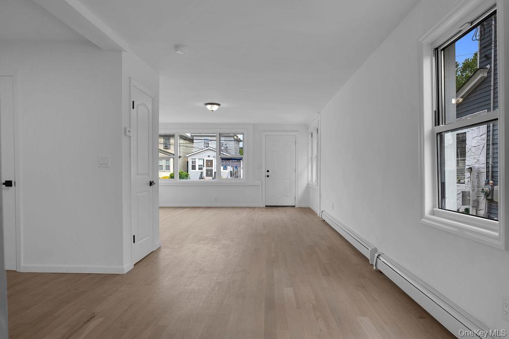173-62 103rd Road Queens, NY 11433 - Photo 18 of 23 a view of an empty room with a window and wooden floor