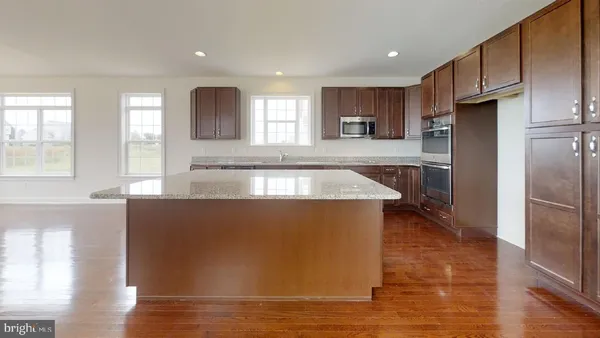 a large kitchen with granite countertop a large counter top stainless steel appliances a sink and a window