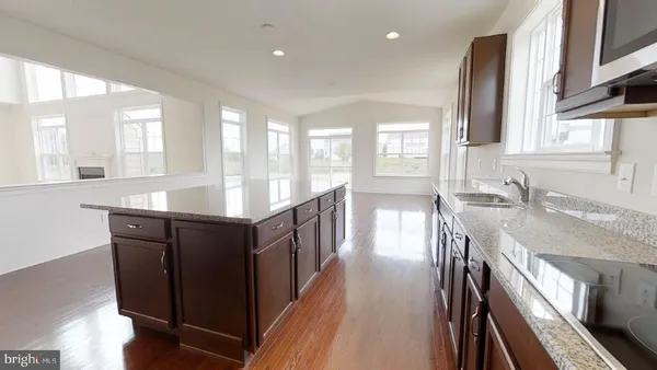 a large kitchen with granite countertop a large counter top a sink a stove and a refrigerator