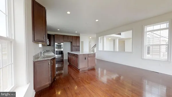 a kitchen with stainless steel appliances granite countertop a stove top oven a sink dishwasher and a refrigerator with wooden floor