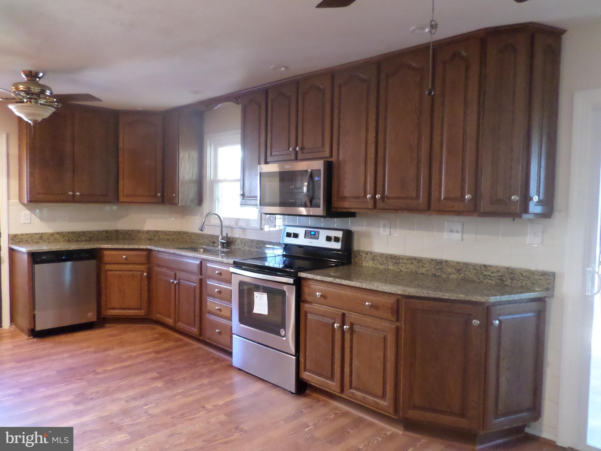 2976 Gracefield Road Silver Spring, MD 20904 - Photo 6 of 25 a kitchen with stainless steel appliances granite countertop wooden cabinets a stove top oven a sink and dishwasher