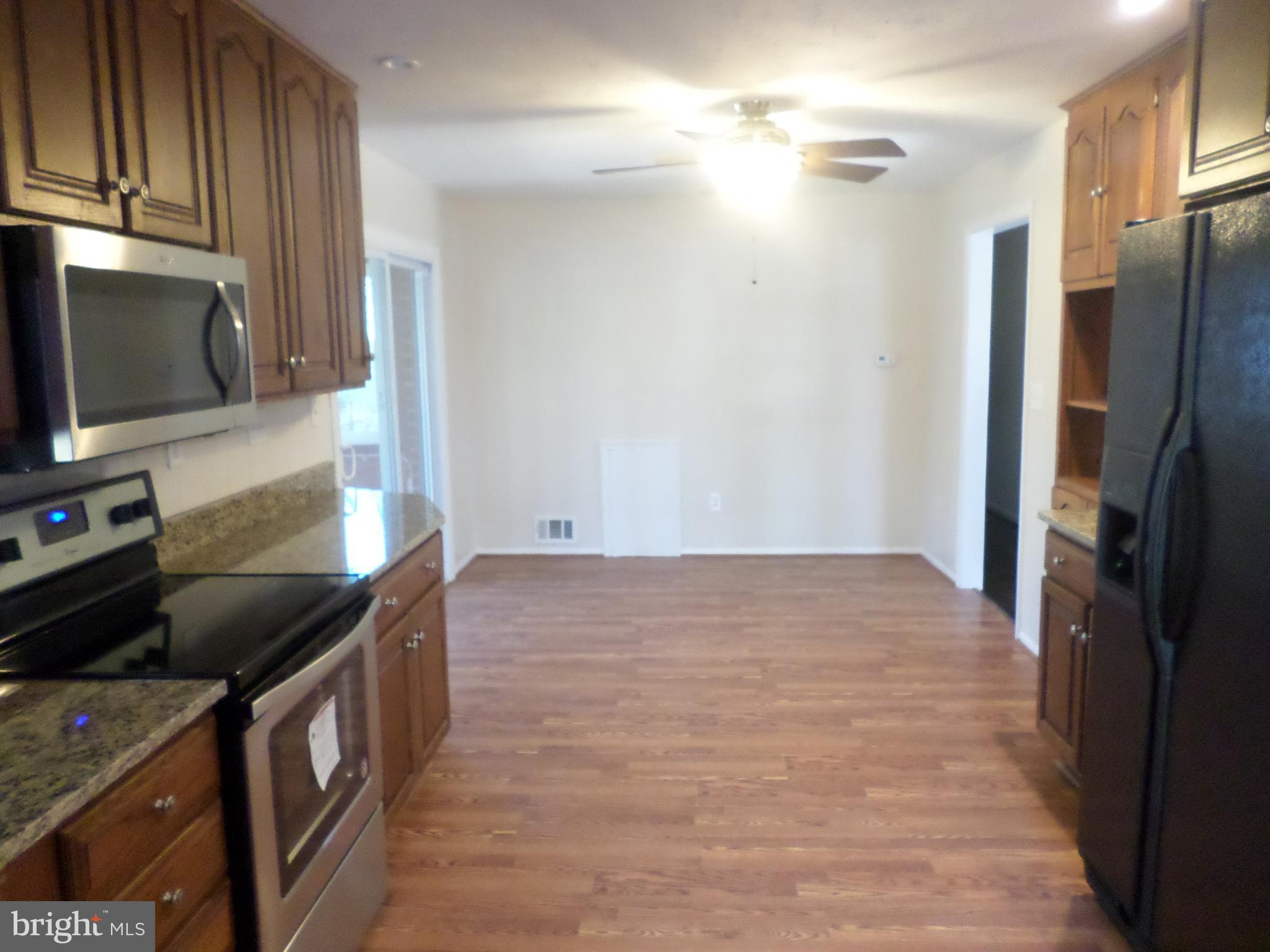 2976 Gracefield Road Silver Spring, MD 20904 - Photo 7 of 25 a kitchen with stainless steel appliances granite countertop a refrigerator a stove and a sink with wooden floor