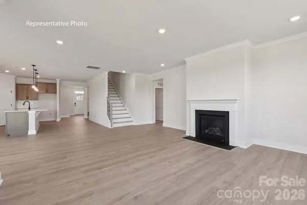 a view of an empty room with wooden floor and a fireplace