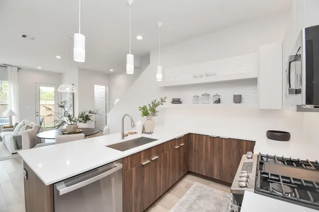 a kitchen with stainless steel appliances a sink dishwasher a stove a dining table with wooden floor