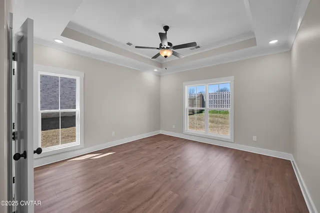 an empty room with wooden floor fan and windows