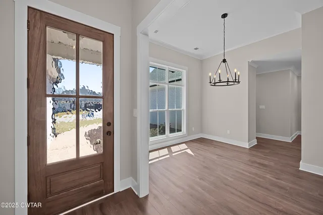 a view of an empty room with window and wooden floor
