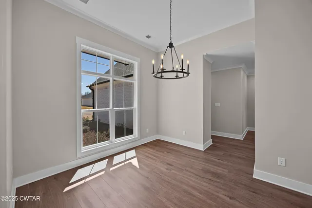 a view of empty room with wooden floor and window