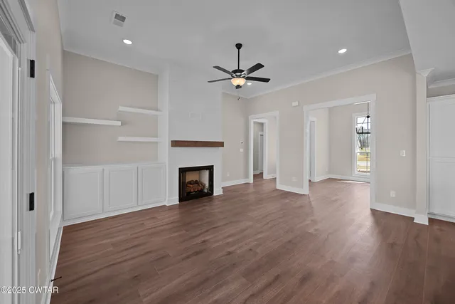 a view of an empty room with wooden floor a fireplace and a window