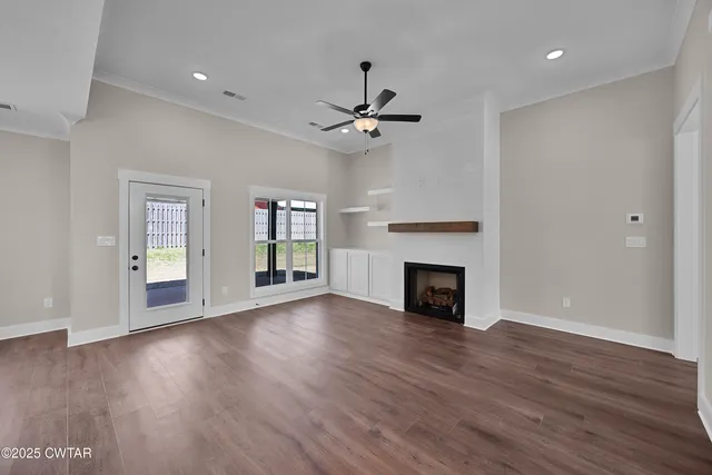 a view of a room with wooden floor fireplace chandelier and windows