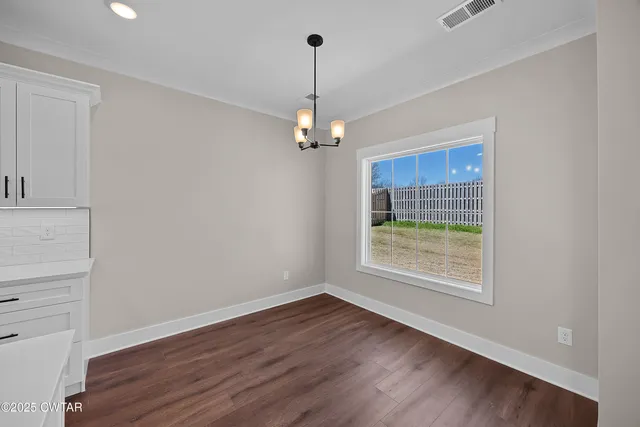 a view of a room with wooden floor chandelier and window