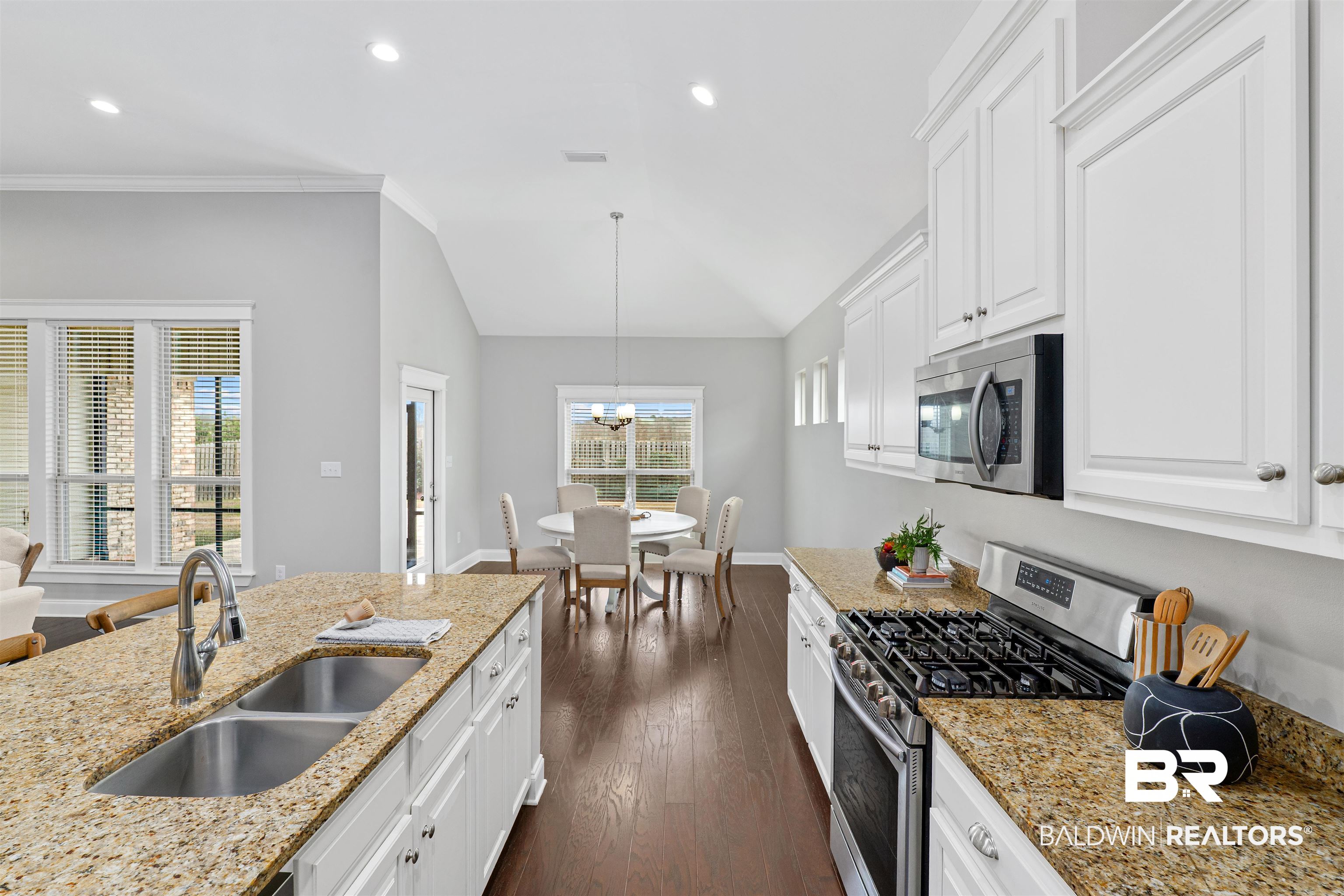 24838 Slater Mill Road Daphne, AL 36526 - Photo 13 of 46 Kitchen featuring appliances with stainless steel finishes, white cabinetry, light stone counters, dark wood-type flooring, and decorative light fixtures