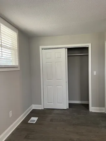 an empty room with wooden floor closet and windows