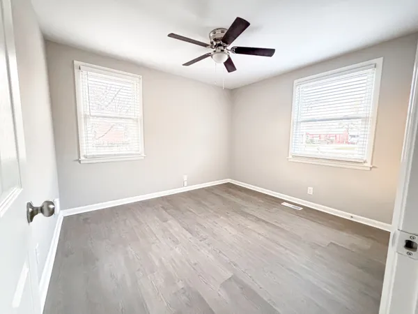 a view of an empty room with a window and wooden floor