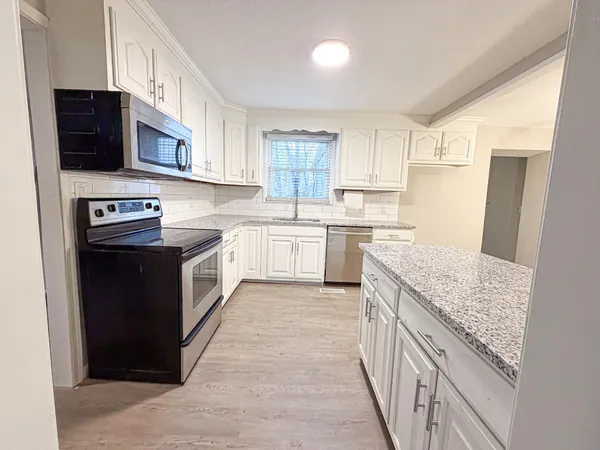a kitchen with stainless steel appliances granite countertop a stove top oven a sink dishwasher and a refrigerator