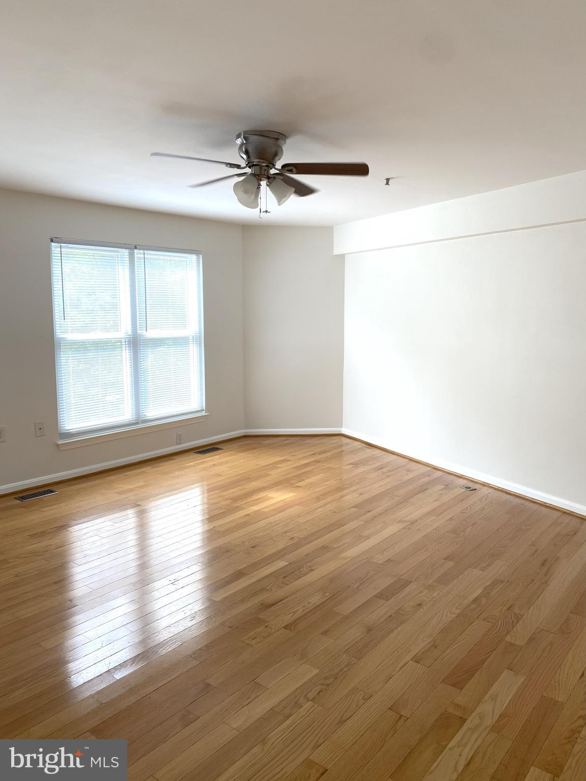 3436 Littleleaf Place Laurel, MD 20724 - Photo 7 of 18 an empty room with wooden floor chandelier fan and windows