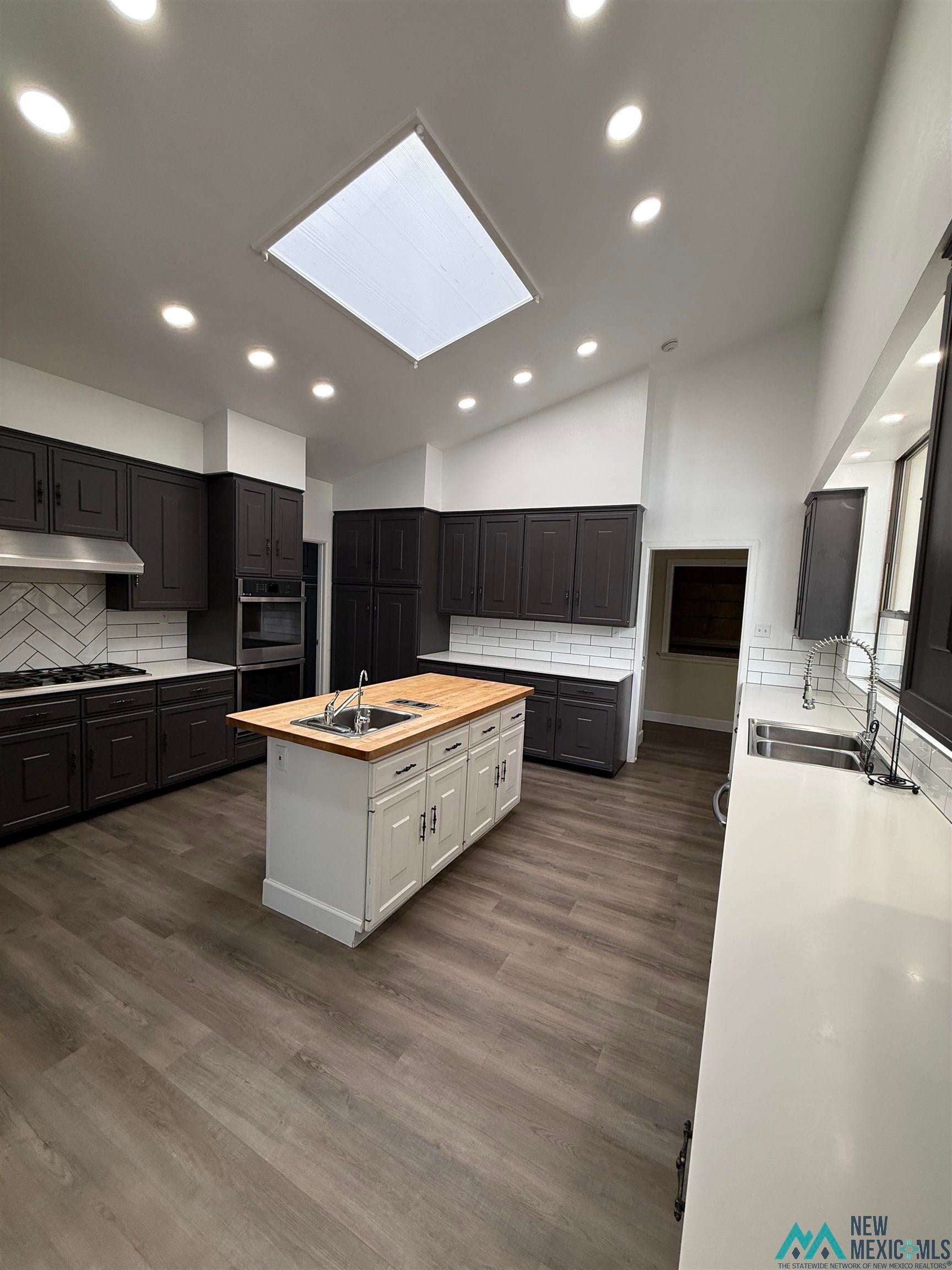 1111 West Country Road Roswell, NM 88201 - Photo 15 of 41 Spacious kitchen featuring a skylight, recessed lighting, and wood-finish flooring