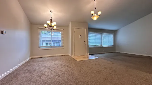 an empty room with windows and chandelier