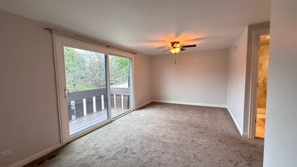 an empty room with chandelier fan and windows