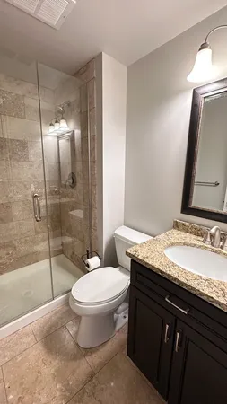 a bathroom with a granite countertop sink toilet a mirror and shower