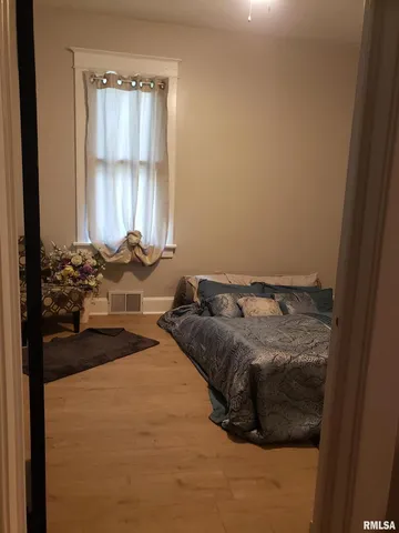 a bed sitting in a bedroom next to a window and a chair