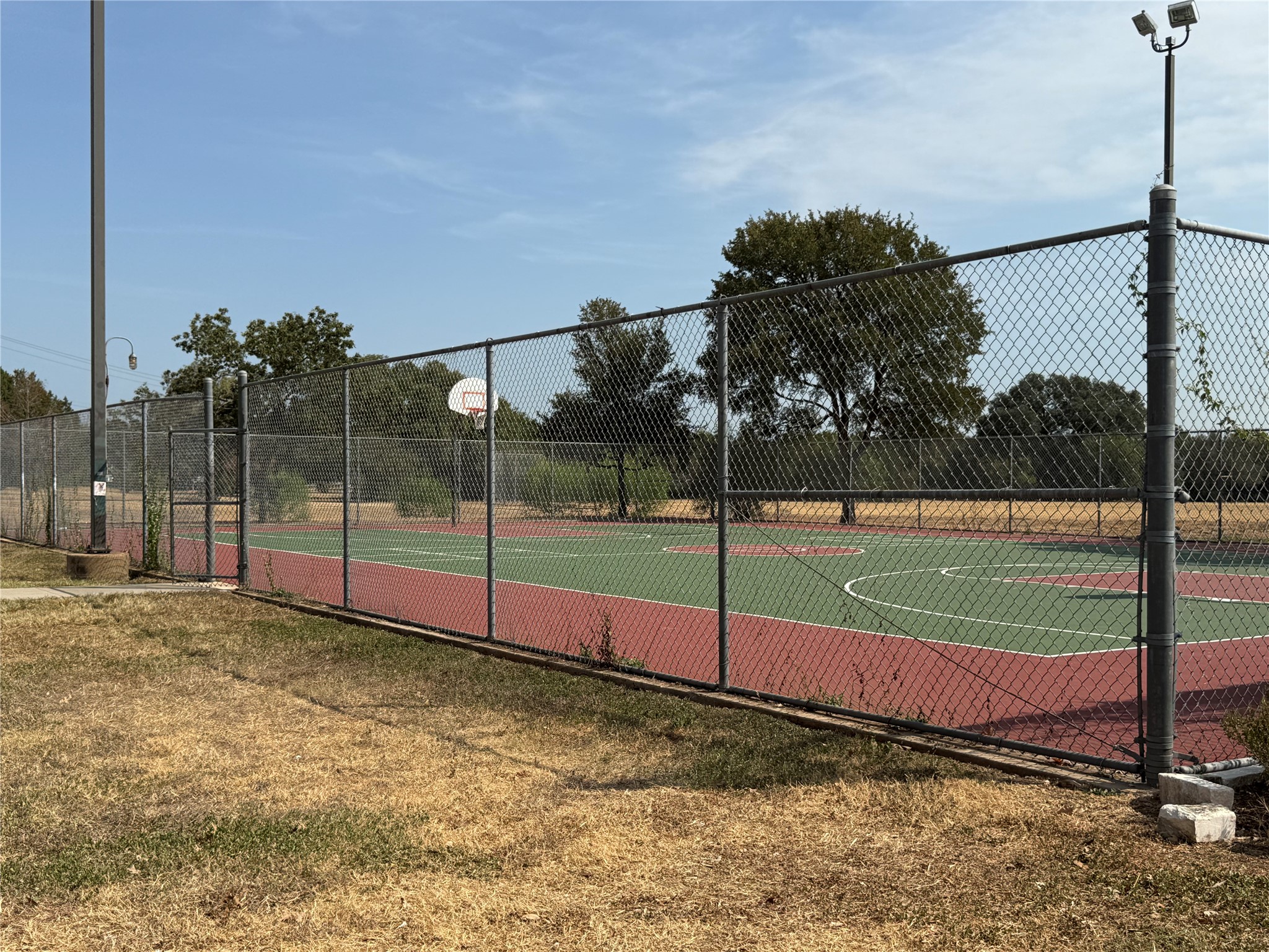 7826 Wheel Rim Circle Austin, TX 78749 - Photo 34 of 38 An outdoor sports court stands fully enclosed by chain-link fencing under a clear sky.