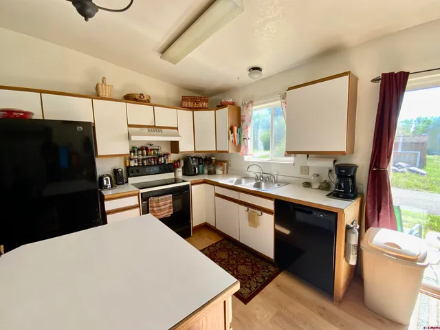 a kitchen with stainless steel appliances a sink cabinets and wooden floor